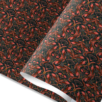 Ornate floral gift wrap with red flowers and fans on dark green background, partially rolled. Illustrated by Lisel Ashlock.