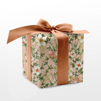 Cube gift box wrapped in pink floral patterned paper with a tan ribbon bow. Illustrated by Lisel Ashlock.