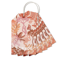 A fan of botanical gift tags in terracotta and pink tones with "FOR YOU" text, illustrated by Lisel Ashlock.
