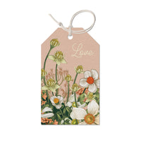 Gift tag with beige background, white anemones with orange centers, green buds, and "Love" text. Illustrated by Lisel Ashlock.