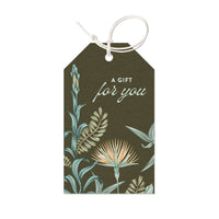 Gift tag with botanical illustration featuring lily flowers and foliage on dark green background reading "A Gift for you". Illustrated by Lisel Ashlock.