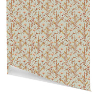 Rolled gift wrap featuring a repeating pattern of brown and rust lily flowers and ferns on a light blue background, illustrated by Lisel Ashlock.