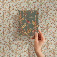 A hand holds a "Giving Thanks" greeting card featuring botanical illustrations against a matching patterned background. Illustrated by Lisel Ashlock.