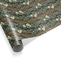 Roll of gift wrap featuring white flowers, red berries, green leaves, and gold ornamental branches on dark background. Illustrated by Lisel Ashlock.