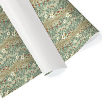 Rolled sheets of sage green gift wrap featuring white flowers and red berries among leaf branches. Illustrated by Lisel Ashlock.