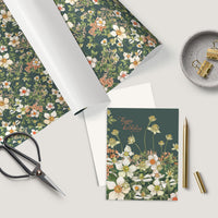 Flat lay of a floral birthday greeting card with coordinating wrapping paper, scissors, pen, and desk accessories. Illustrated by Lisel Ashlock.
