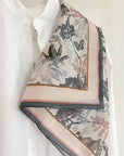 Angelite silk cotton scarf with botanical and butterfly print in cream, pink, and charcoal draped over white shirt. Illustrated by Lisel Ashlock.