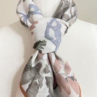 Silk cotton scarf in cream with blue, gray, and mauve botanical leaf patterns, gathered at center. Illustrated by Lisel Ashlock.