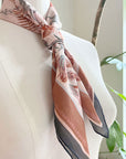 Sunstone silk cotton scarf with botanical leaf patterns in terracotta and gray tones, draped on a mannequin. Illustrated by Lisel Ashlock.