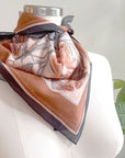 Sunstone silk cotton scarf draped on mannequin with decorative figures and earth tones. Illustrated by Lisel Ashlock.