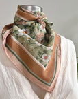 Floral silk cotton scarf in green and blush tones tied around mannequin neck. Illustrated by Lisel Ashlock.