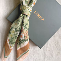 Silk cotton scarf in Anemone Ceylon Green with floral pattern, displayed with gray Linna box. Illustrated by Lisel Ashlock.