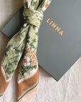 Silk cotton scarf in Anemone Ceylon Green with floral pattern, displayed with gray Linna box. Illustrated by Lisel Ashlock.