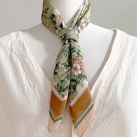 Silk cotton scarf with anemone floral pattern in green, cream, and gold tones, tied at neck. Illustrated by Lisel Ashlock.