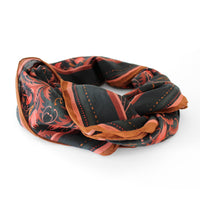 Folded silk cotton scarf in bright mahogany with filigree patterns and striped details. Illustrated by Lisel Ashlock.