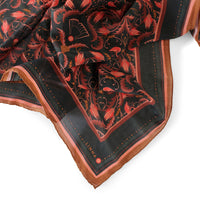 Silk cotton scarf featuring red and orange filigree floral design on dark background with mahogany border. Illustrated by Lisel Ashlock.