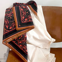 Silk cotton scarf with bright mahogany filigree pattern draped over wooden chair. Illustrated by Lisel Ashlock.