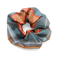 Folded blue and rose striped silk scrunchie with polka dot pattern and tan edges on white background. Illustrated by Lisel Ashlock.