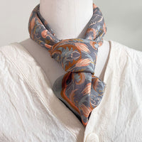 Apricot Filigree silk cotton scarf tied around a mannequin wearing a cream linen shirt. Illustrated by Lisel Ashlock.