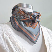 A silk cotton scarf with apricot filigree pattern draped around a mannequin wearing a white shirt. Illustrated by Lisel Ashlock.