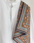 A white button-up shirt styled with an apricot filigree silk cotton scarf featuring orange and gray stripes. Illustrated by Lisel Ashlock.