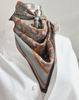 Apricot Filigree silk cotton scarf displayed on a dress form with ornate floral pattern in orange and charcoal. Illustrated by Lisel Ashlock.