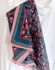 Colorful silk cotton scarf with blue rose filigree pattern draped on white mannequin. Illustrated by Lisel Ashlock.