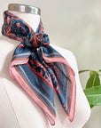 Blue rose filigree silk cotton scarf draped on a dress form mannequin next to a potted plant. Illustrated by Lisel Ashlock.