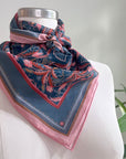 Blue rose filigree silk cotton scarf with pink border tied around mannequin neck. Illustrated by Lisel Ashlock.