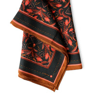 Silk twill scarf featuring red filigree floral pattern on black with brown border detail, illustrated by Lisel Ashlock.