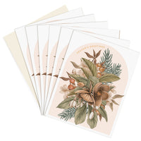 A fanned stack of Season's Greetings cards featuring an illustrated hellebore flower arrangement in brown and green tones on blush background. Illustrated by Lisel Ashlock.