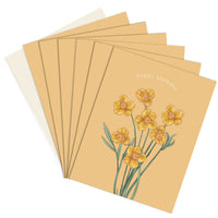 A stack of happy birthday greeting cards featuring yellow buttercup flowers on a tan background. Illustrated by Lisel Ashlock.