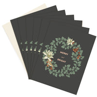 Stack of "Merry and Bright Wreath" greeting cards with dark background and floral design. Illustrated by Lisel Ashlock.