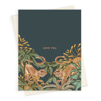 A navy greeting card featuring two monkeys among golden flowers and green foliage with "LOVE YOU" text. Illustrated by Lisel Ashlock.