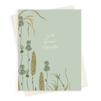 Sympathy greeting card featuring wilting flowers and seed pods on a sage green background with white text reading "With Deepest Sympathy." Illustrated by Lisel Ashlock.