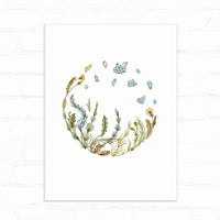 Watercolor illustration of herbs and crystals arranged in a circular wreath with gold and green botanical elements. Illustrated by Lisel Ashlock.