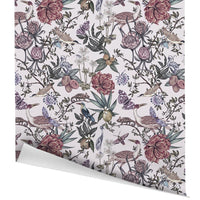 Rolled gift wrap featuring intricate botanical illustrations of flowers, birds, and butterflies in purple and green tones. Illustrated by Lisel Ashlock.