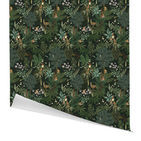 A rolled gift wrap with a dark green woodland pattern featuring ferns, flowers, animals and gnomes. Illustrated by Lisel Ashlock.