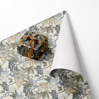 Rolled gift wrap with botanical fern and butterfly pattern in sage and cream tones, tied with brown ribbon. Illustrated by Lisel Ashlock.