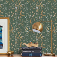 A wooden desk against green botanical wallpaper with gold lamp, books, and decorative objects. Illustrated by Lisel Ashlock.