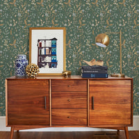 Mid-century modern wooden dresser against green botanical wallpaper with styled decor. Illustrated by Lisel Ashlock.