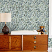 Secret Garden Wallpaper in Robin Egg covers a bedroom wall above a mid-century modern wooden dresser. Illustrated by Lisel Ashlock.