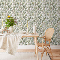 A dining area with botanical wallpaper, wooden table, rattan chair, and white linens. Illustrated by Lisel Ashlock.