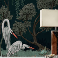 Night Heron Mural in Ebony featuring two white herons among trees with a lamp on a wooden dresser. Illustrated by Lisel Ashlock.