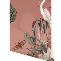 Wallpaper featuring a white heron among botanical elements and a moth on a dusty rose background. Illustrated by Lisel Ashlock.