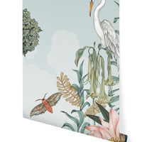 Illustrated wallpaper mural featuring a white heron, flowering plants, a butterfly, and botanical elements on a sage background by Lisel Ashlock.