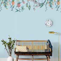 A light blue nursery wall features a hanging floral mural with pink and purple flowers above a wooden crib with cream bedding. Illustrated by Lisel Ashlock.