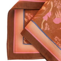 Sienna silk cotton scarf featuring warm brown, orange, and pink botanical patterns with layered folds. Illustrated by Lisel Ashlock.