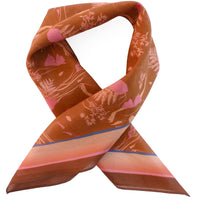 Silk cotton scarf in sienna with botanical print and pink heart details, twisted into a ribbon shape. Illustrated by Lisel Ashlock.