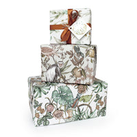 Three stacked gift boxes wrapped in botanical patterns with a brown ribbon and gift tag, illustrated by Lisel Ashlock.